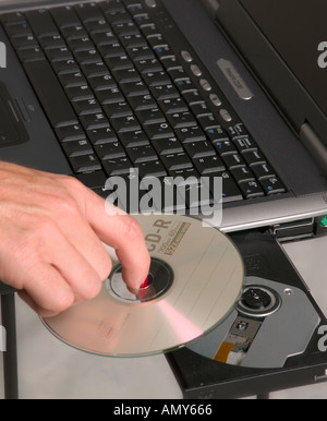 La donna caucasica mano inserire il CD nel computer portatile. usa Foto Stock