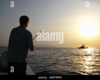 Uomo di pesca barca off con sunrise in background vicino a Puerto Vallarta, Messico Foto Stock