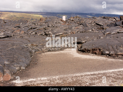 Il flusso di lava dal vulcano Kilauea solidificato intorno a nessun traffico permanente segno sulla vecchia east coast road della Big Island delle Hawaii Foto Stock