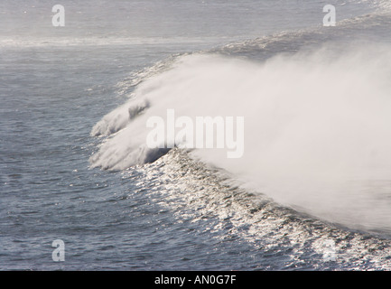 Semi parete circolare di onda surf la laminazione in Saunton Sands Bay con off shore vento spray North Devon England Foto Stock