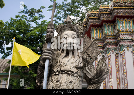 Il gigante custode presso il cancello di Wat Pho (il Tempio del Buddha Reclinato) Wat Phra Chetuphon Bangkok, Thailandia, & Re Tailandese bandiera. Foto Stock