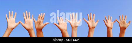 Fila di mani con le palme aperte sul cielo blu sullo sfondo Foto Stock