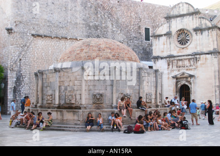 Turisti che si siedono attorno al grande grande Onofrio fontana velika Onofrijeva Placa Stradun Dubrovnik, città vecchia. Costa della Dalmazia, Croazia, Europa. Foto Stock