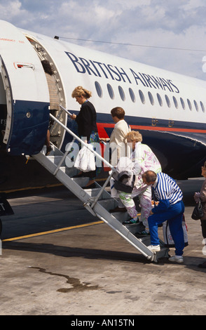 Passeggeri a piedi passi fino a salire a bordo del velivolo sulla pista di aeroporto. Foto Stock