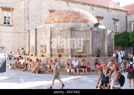 Turisti che si siedono attorno al grande grande Onofrio fontana velika Onofrijeva Placa Stradun Dubrovnik, città vecchia. Costa della Dalmazia, Croazia, Europa. Foto Stock