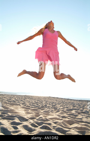 Giovane donna saltando al fronte spiaggia Foto Stock