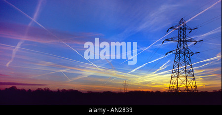 Sentieri di vapore in inizio di mattina di cielo e pilone silhouette. Foto Stock