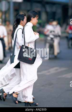 Scena di strada / donne che indossano Ao-dai / abito tradizionale, la città di Ho Chi Minh (Saigon), Vietnam Foto Stock
