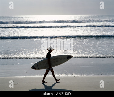 La spiaggia di Kuta / Surfer camminando lungo la spiaggia / Tramonto, Bali, Indonesia Foto Stock