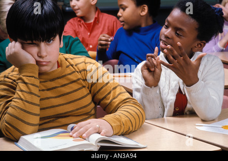African American studentessa noioso Caucasian boy in una scuola elementare classroom Foto Stock