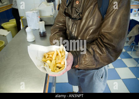 Un uomo tiene un sacco di tipo tradizionale di chip britannico avvolto nella carta. Foto Stock