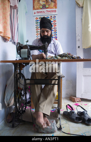 La religione Sikh locale utilizzando una macchina da cucire nel suo negozio a Manali Foto Stock