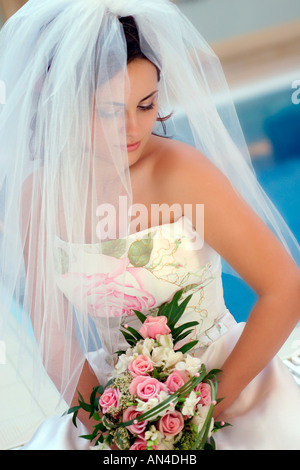 Un ritratto di una sposa il giorno delle nozze nella foto tenendo un mazzo di fiori e indossando un bianco abito da sposa Foto Stock