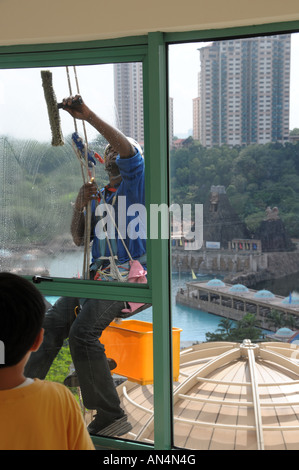 Operai stranieri la pulizia di vetri al Sunway Lagoon, Malaysia senza utilizzare una gondola Foto Stock