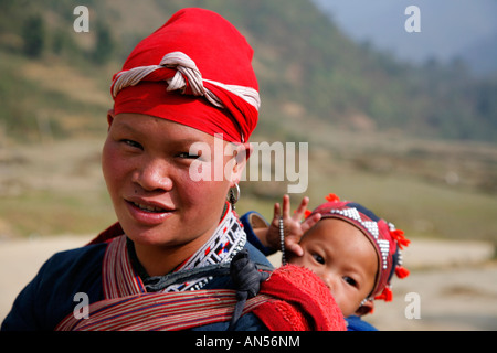 Red Dzao tribeswoman con il bambino sulla schiena Foto Stock