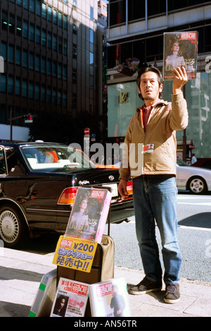 Senzatetto uomo vendere l'edizione giapponese del grande problema su Tokyo di Ginza. Foto Stock