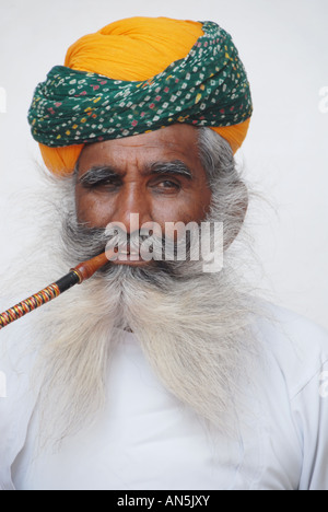 Un barbuto Rajasthani uomo in un turbante tradizionale fuma un narghilè fumatore a Jodhpur fort, India. Foto Stock