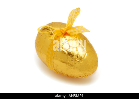 Easter Egg in gold foil with yelloe ribbon on white background Foto Stock