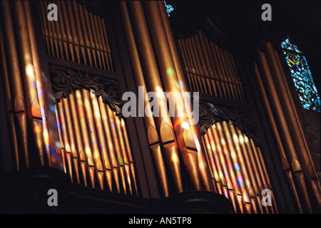 Colori dalle vetrate nella cattedrale di Birmingham cadere sull'organo a canne come sole splende attraverso. Foto Stock