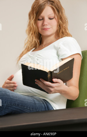 Una donna in stato di gravidanza della lettura della Bibbia Foto Stock