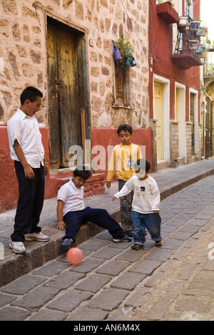 Messico Guanajuato quattro figli maschi che giocano a calcio nel vicolo stretto tra gli edifici gli edifici colorati Foto Stock