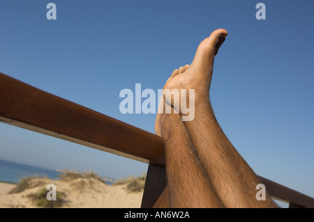 L'uomo piedi sollevati in aria, rilassante su una struttura di legno, gambe incrociate Foto Stock