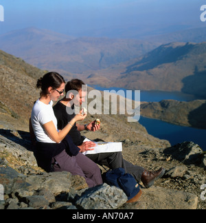 Gli escursionisti di mangiare le mele di prendere un periodo di riposo e guardando una mappa mentre si cammina fino a Mount Snowdon nella primavera del Parco Nazionale di Snowdonia Wales UK KATHY DEWITT Foto Stock