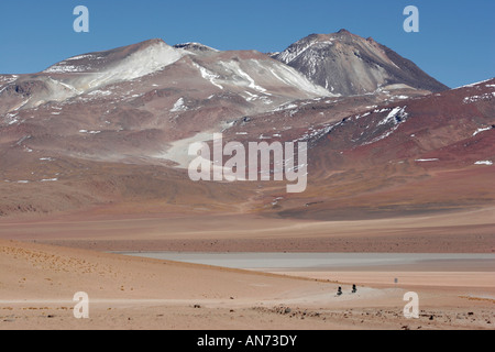 Due ciclisti sopraffatte da montagne innevate vicino a Laguna Verde sull'altiplano del sud-ovest della Bolivia Foto Stock