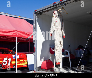 Uniforme tuta racing si blocca nel retro del rimorchio transporter di bianco e nero con pavimento a scacchi in attesa di essere nominato tempo di gara Foto Stock