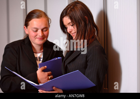 Due ragazze adolescenti tenendo le cartelle in un ambiente di ufficio REGNO UNITO Foto Stock