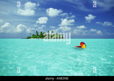Il relax di una vacanza da sogno sul materasso ad aria sotto ombrellone colorato vicino al piccolo deserto isola in paradiso Foto Stock