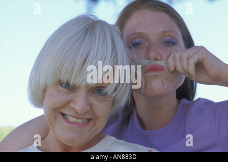 Ritratto di 57 anno vecchia donna caucasica con 22 anni di figlia che sta facendo un 'baffi finti' con sua madre s capelli Foto Stock