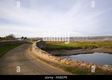 Sentiero costiero percorso lungo il vicolo del paese e ponte vecchio attraverso Afon Nodwydd Fiume con vista ovest al rosso Wharfe Bay Anglesey nel Galles Foto Stock