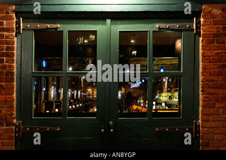 Matura in un invitante bar visto di notte attraverso pesanti porte verdi a Distillery District Toronto Foto Stock