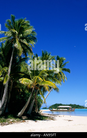 Una spiaggia da cartolina e una canoa polinesiana in remoto atollo Aitutaki Cook Islands palme spiaggia fiancheggiata. Foto Stock