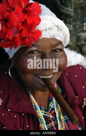 Un cubano signora vestita in costume tradizionale fuma un sigaro. Foto Stock