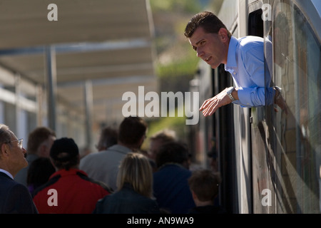 Il treno italiano inclinazione pilota al di fuori della sua finestra della cabina e sta parlando di un passeggero sulla piattaforma di occupato. Foto Stock