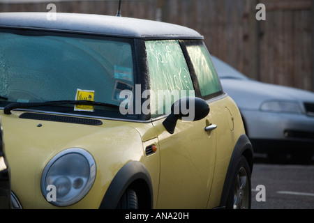 Un Mini auto con un biglietto di parcheggio e un permesso di parcheggio e le parole 'il tuo intaccata" (sic) scritto in la brina sul vetro. Foto Stock