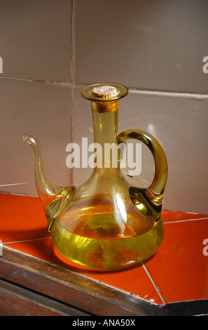 Lo spagnolo golden olio d'oliva in decanter su orange superficie piastrellata Foto Stock