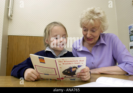 Ragazza giovane legge alla sua nonna REGNO UNITO Foto Stock