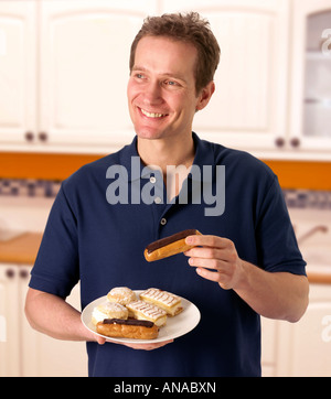 Uomo in cucina con torte di panna Foto Stock