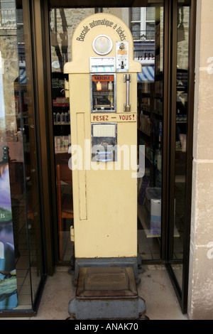 In vecchio stile a gettone pesa pubblica la macchina al di fuori di una farmacia di Bayeux in Normandia Francia Foto Stock