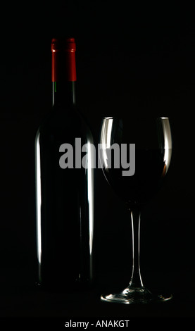 Una bottiglia e un bicchiere di vino rosso Foto Stock