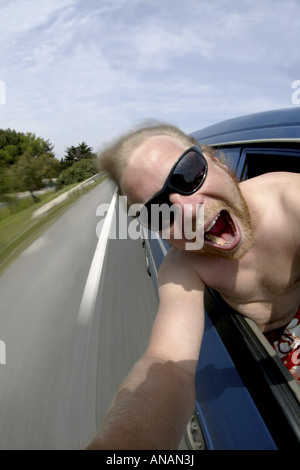 Giovane biondo Uomo con occhiali da sole rendendo un autoritratto in un'auto in movimento Foto Stock