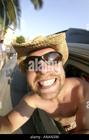 Giovane biondo Uomo con occhiali da sole rendendo un autoritratto in un'auto in movimento Foto Stock