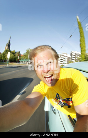 Giovane biondo uomo che fa un autoritratto in un'auto in movimento Foto Stock