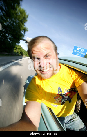 Giovane biondo uomo che fa un autoritratto in un'auto in movimento Foto Stock