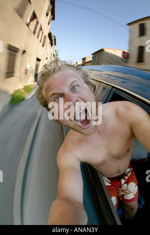 Giovane biondo uomo che fa un autoritratto in un'auto in movimento Foto Stock