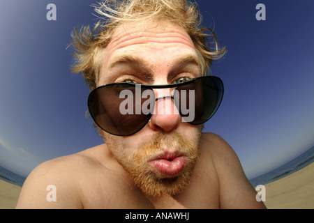 Giovane uomo biondo con gli occhiali da sole facendo una faccia Foto Stock