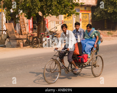 Paio di persone a cavallo di risciò bicicletta con l'uomo la pedalata nella parte anteriore lungo la strada tipica in città il Rajasthan in India Foto Stock